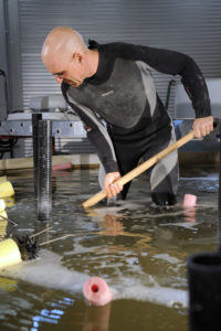 Dr. Lenny Tender, a microbial electro-chemist at the U.S. Naval Research Laboratory, wades in a mesocosm he used to develop his Benthic Microbial Fuel Cell. The facility, housed in the NRL’s Laboratory for Autonomous System Research, contains 18 inches of seawater and 24 inches of synthetic marine sediment. Credit:Jamie Hartman, U.S. Naval Research Laboratory 