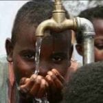 Cropped image of a child drinking water from a faucet