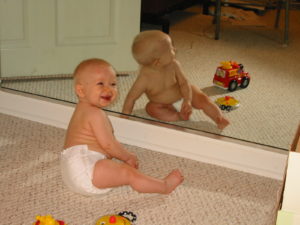 My daughter experiencing the joy in discovering herself in the mirror for the first time.