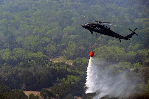 A Texas National Guard Uh-60 Black Hawk helicopter drops water to help fight the wildfires affecting the Possum Kingdom Lake area in North Texas.  Wildfires are a result of extreme drought conditions. Photo by SSG Malcolm McClendon.