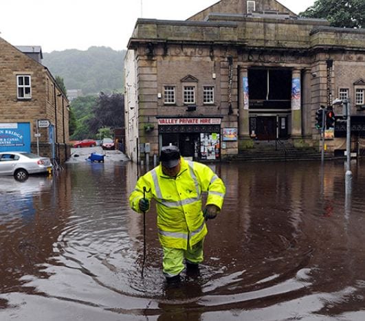 photo of a man wading through flood waters in northern england. Credit: the guardian