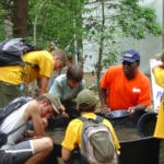Photograph of a USGS employee encircled by children learning about earth science. Image Credit: USGS.