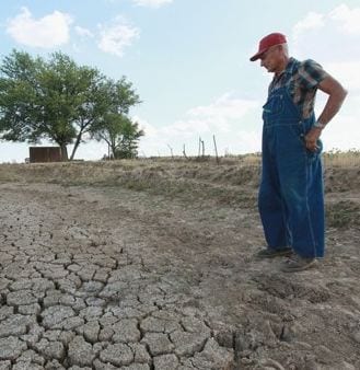 Image of a farmer examining a dry, cracked area. Credit: Washington Post