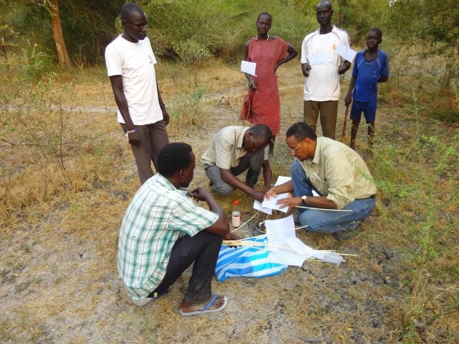 A photo showing the use of sticky-paper traps for capturing Phlebotomus orientalis, the sand fly vector of Visceral leishmaniasis. Pictured here are Dr. Dia Elnaiem (right), Constantino Doggale (head of medical entomology, Federal Ministry of Health, Republic of South Sudan) and local staff at Old Fangak, Jonglei State, South Sudan. They are exploring the possibility of using this method for routine surveillance of the vector. Image Credit: Dia-Eldin A Elnaiem.