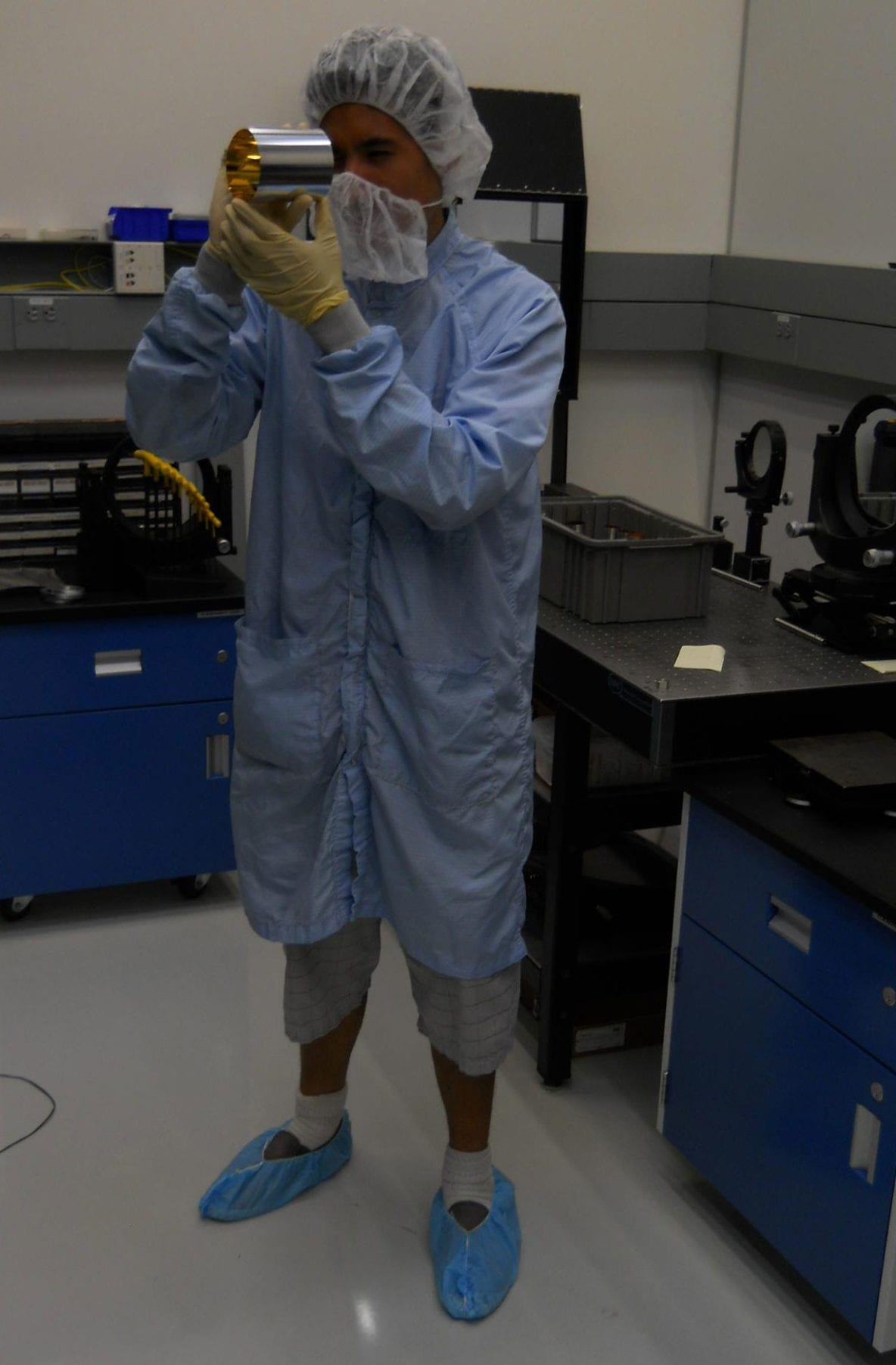 Goddard intern Billy Barrios performing an optical check on one of the NICER OpticÛªs mirrors. Image Credit: URC.