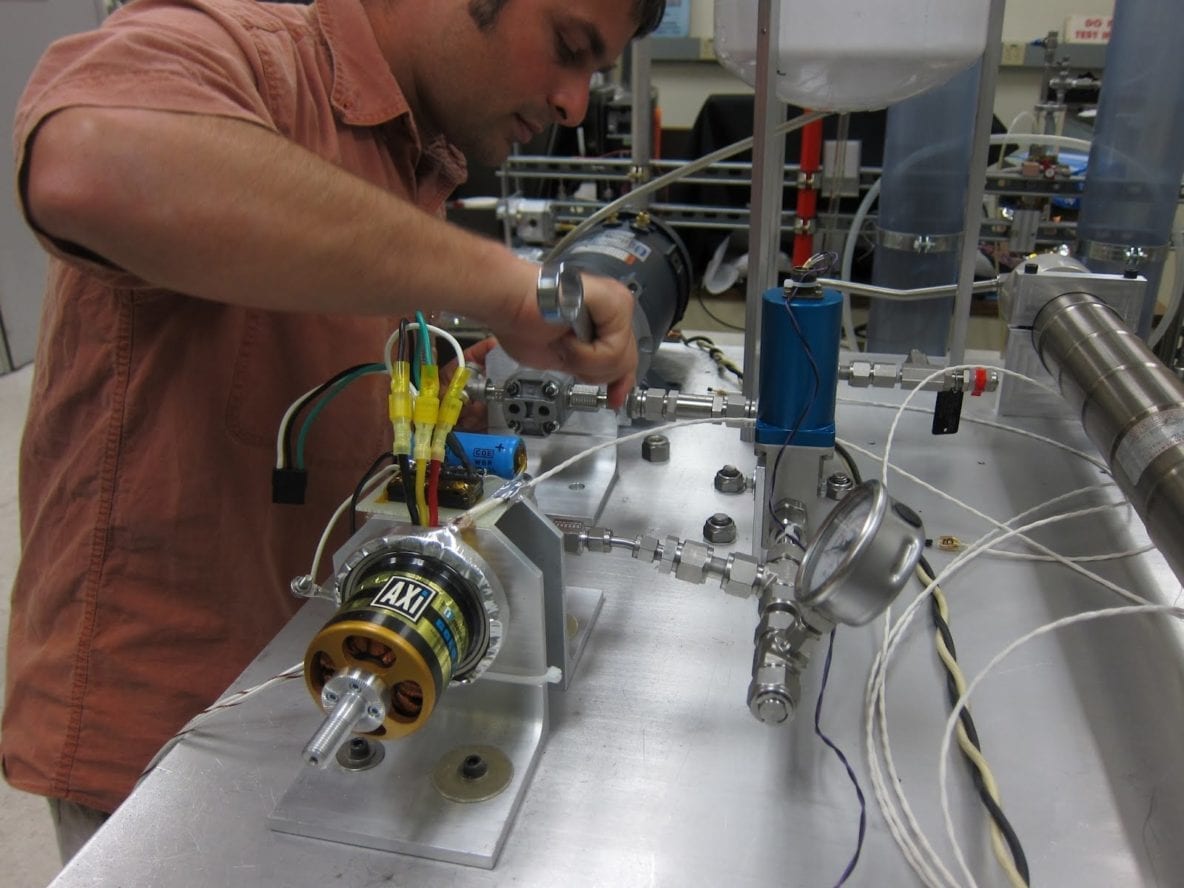 Photo of Mechanical engineering researcher Kalind Carpenter assembling the SOLO TREC Power generation subsystem test rig. Image Credit: URC.